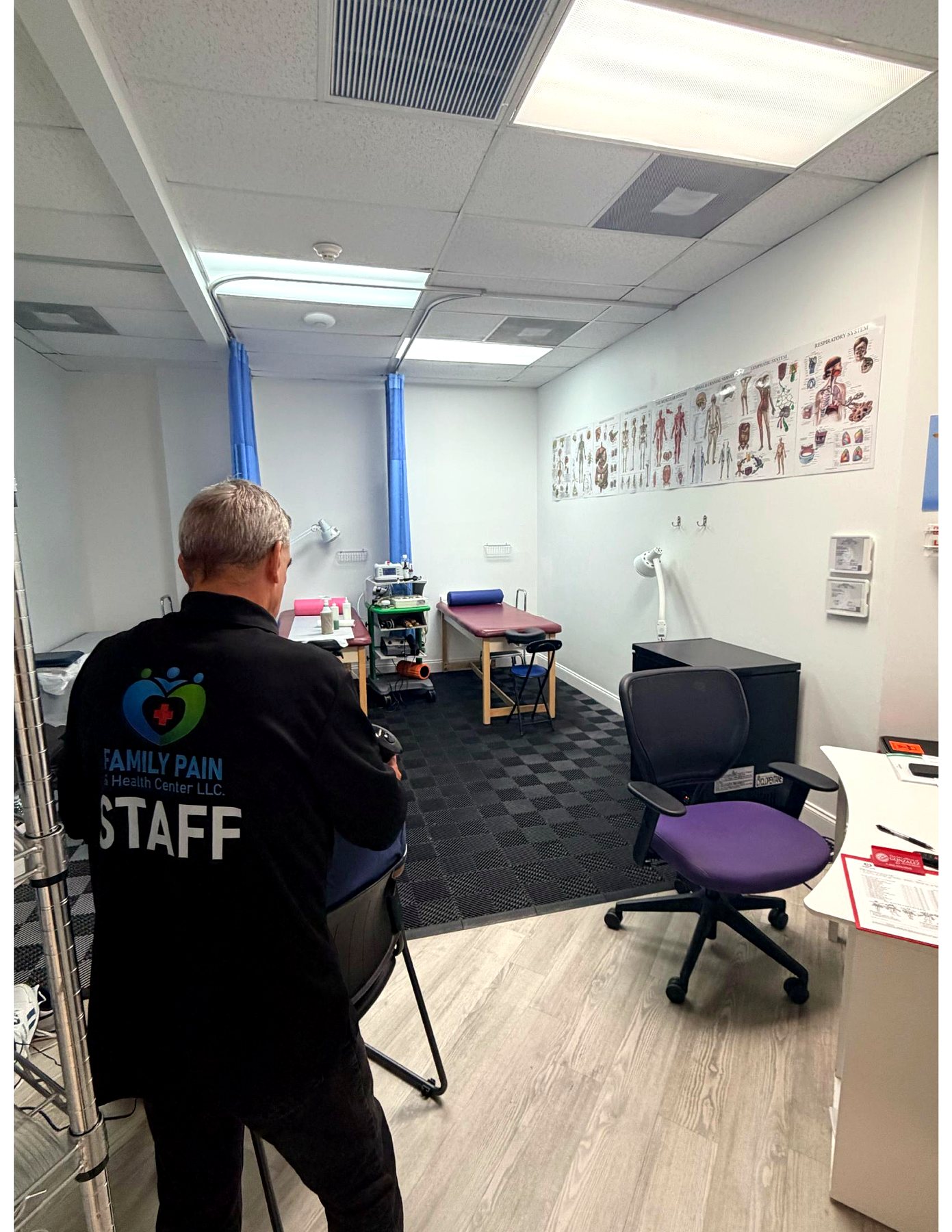 The physical therapy treatment room with curtained treatment tables, therapy modalities and anatomy charts