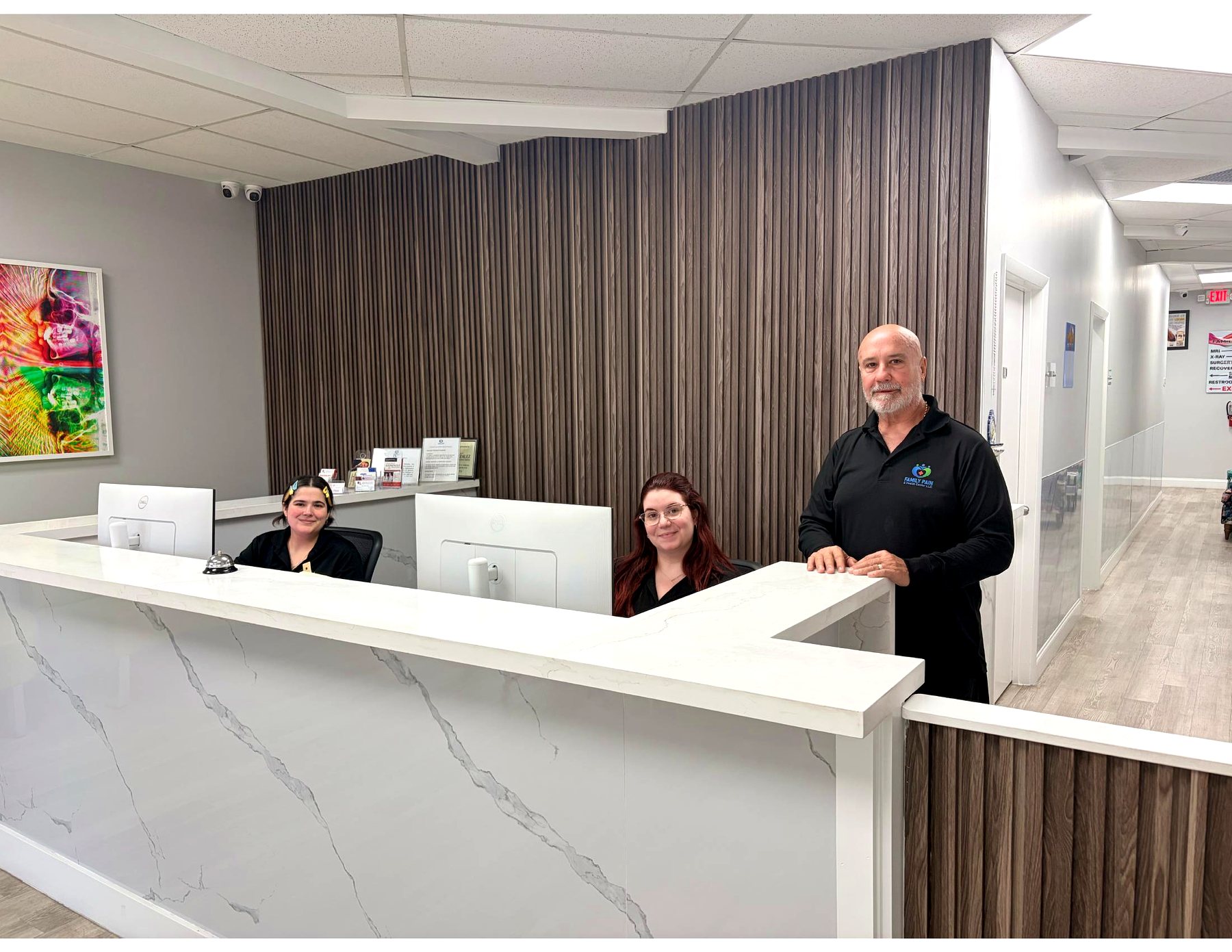 The front desk team of Family Pain & Health Center standing at the marble reception counter