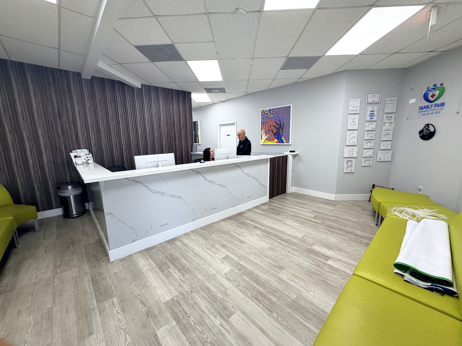 The reception and waiting area at Family Pain & Health Center, with a white marble front desk and lime green seating